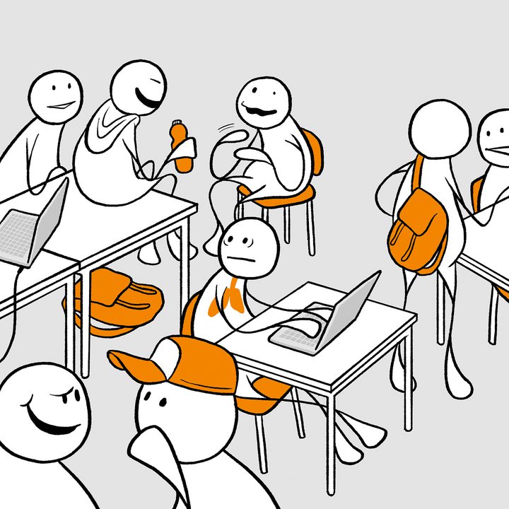 Et klasserom med elever. Det er flere elever som snakker sammen i grupper. I midten sitter en elev på en pult med en pc og har et stresset utrykk i ansiktet.